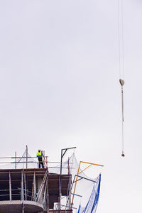 Low angle view of people on street light against clear sky