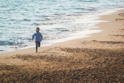 Rear view of man walking at beach