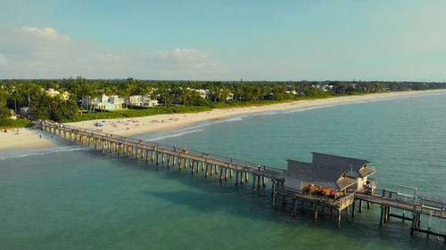 Pier in naples by aerial drone. drone flies around a fishing pier in naples. naples beach pier.