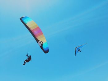 Low angle view of parachuting against clear blue sky