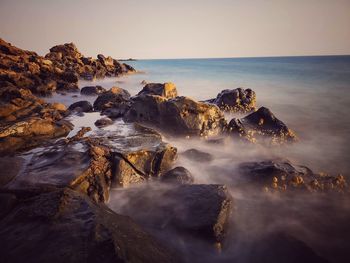 Scenic view of rocks in sea against sky