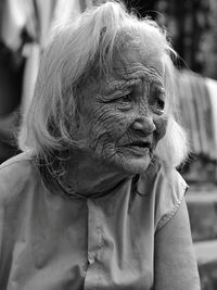 Close-up of senior woman looking away while sitting outdoors