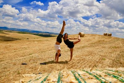 Full length of man doing handstand by young woman on agricultural field