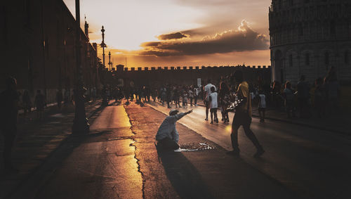 People walking on street in city at sunset