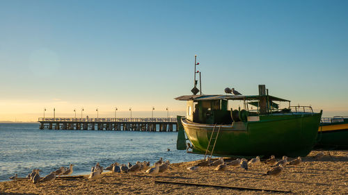 Ship moored at pier against sky during sunset