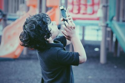 Cute boy using cell phone at playground