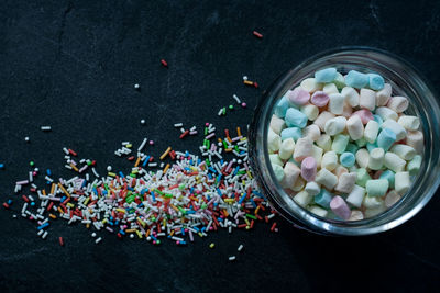 High angle view of multi colored candies and sprinkles on slate