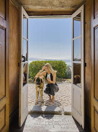 Woman with smart phone squatting by dog