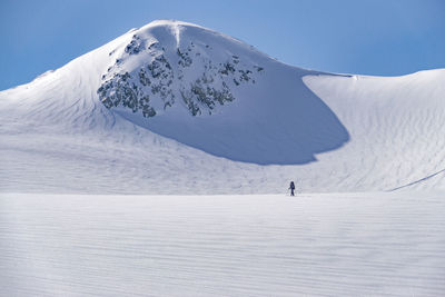 Man skiing on snow covered field against sky