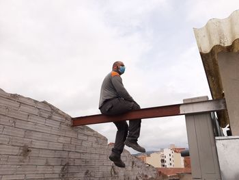 Low angle view of man sitting on metal structure