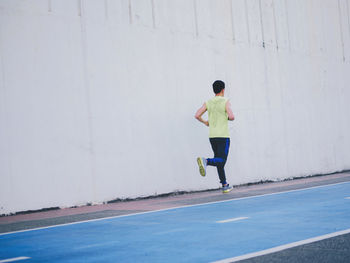 Rear view of man running on wall