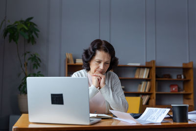 Portrait of young woman using laptop at home