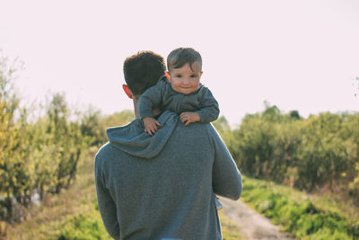 Portrait of cute son carrying by father on land