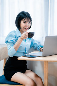 Young woman using laptop while sitting on table