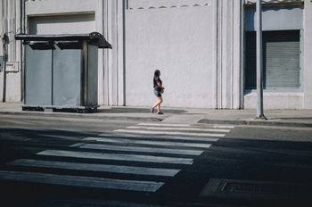FULL LENGTH OF WOMAN WALKING ON STREET AGAINST BUILDINGS