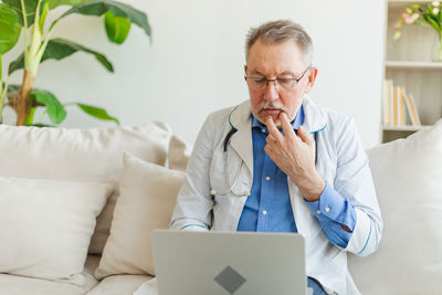 Young man using laptop while sitting on sofa at home