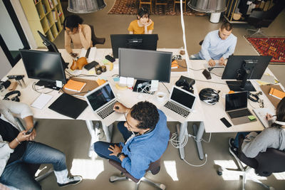 High angle view of business people using technologies while working at desk in office