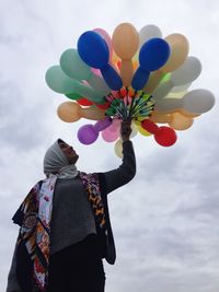 Low angle view of woman with balloons against sky