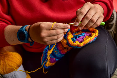 Young woman's hands crocheting with crochet hook and yellow yarn