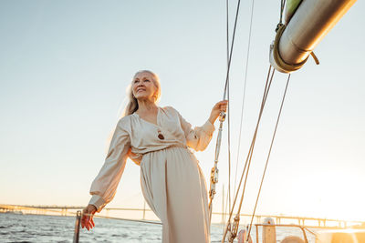 Senior woman standing at sailboat in sea