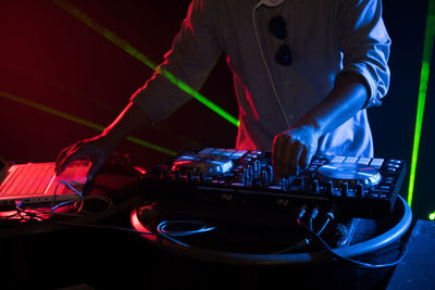 Midsection of dj mixing sound at nightclub