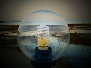 Close-up of crystal ball on sea against sky