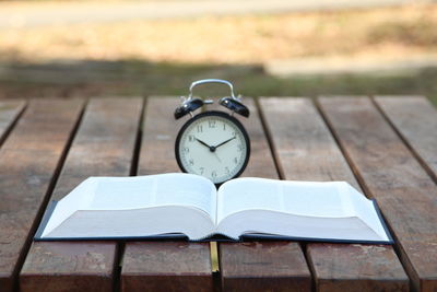 Close-up of alarm clock on book at table