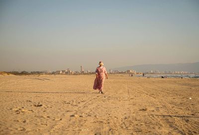 Woman standing on beach against clear sky