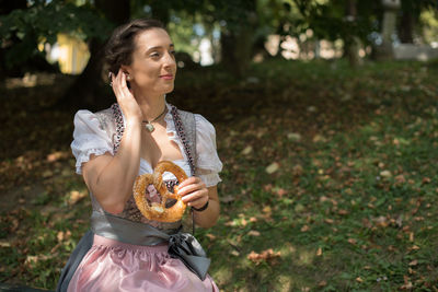Woman having pretzel while sitting on field