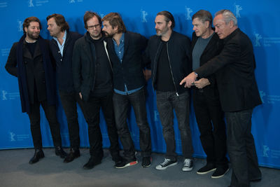 Young men standing against blue wall