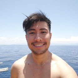 Portrait of smiling young man against sea
