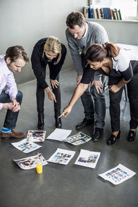 Mid adult businesswoman pointing at photographs while discussing with colleagues in office