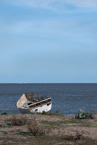 Abandoned boat on beach against sky