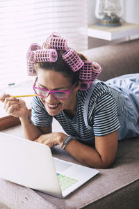 Woman with hair curlers using laptop at home