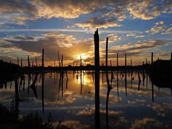 Silhouette wooden posts in lake against sky during sunset, bavaro - republic dominican