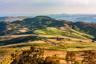 Landscape of harvest time with road that snakes half towards horizon and gets lost in the mountain.