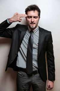 Young businessman gesturing against wall