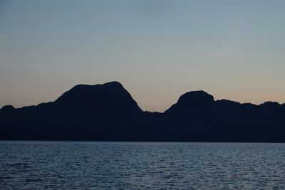 Scenic view of sea and silhouette mountains against sky at sunset