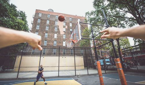 Cropped hands of person against man playing basketball at court