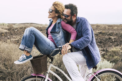 Side view of couple riding bicycle on field