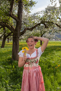 Happy girl standing by tree against plants