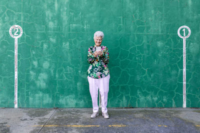 Full length of woman standing against wall