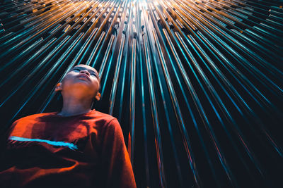 Low angle view of boy standing against patterned wall