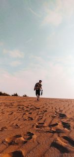 Full length of man on rock in desert against sky