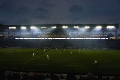 Group of people playing soccer field against sky at night