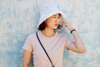 Portrait of a beautiful young woman standing against wall