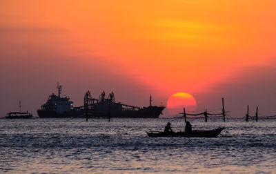 Silhouette boats in sea against sky during sunset