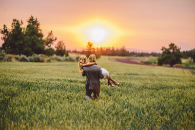 Woman on field against sky during sunset