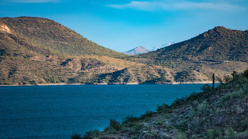 Scenic view of sea and mountains against blue sky
