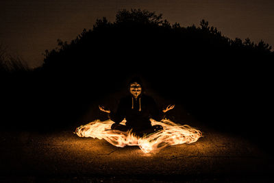 Man sitting on fire in the dark
